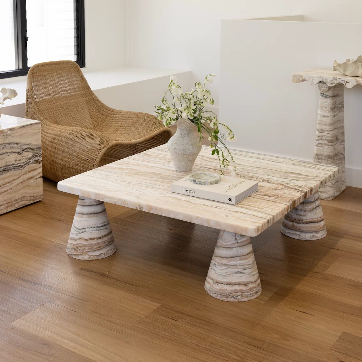 Light striped marble coffee table next to rattan chair