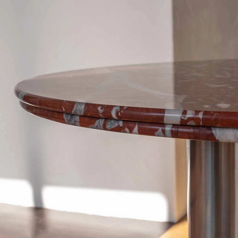 Red veined marble round table with stainless steel legs - styled with decor & books in modern space