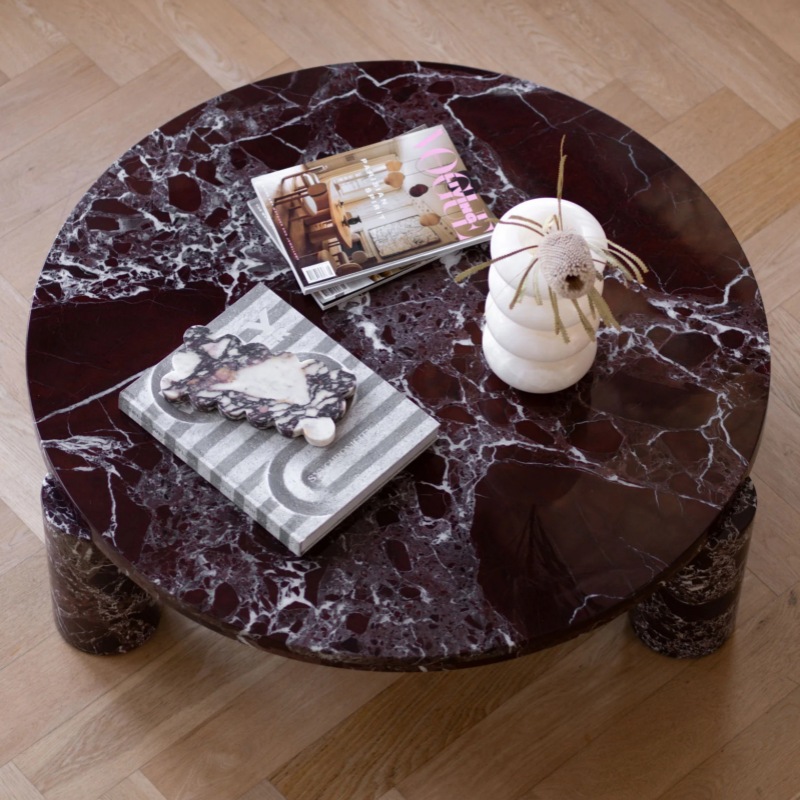 Top-down view of burgundy marble coffee table - styled with magazines & decorative vase