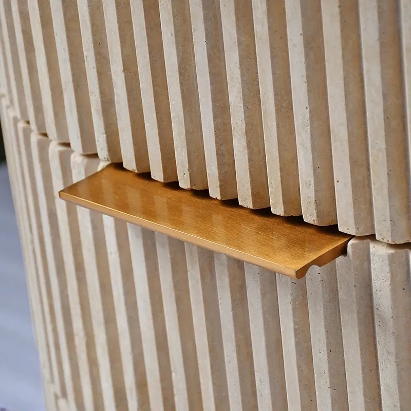 Close-up of travertine ribbed nightstand drawer - brass handle and fluted stone texture detail